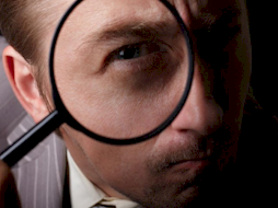 guy looking at fake drivers license under magnification glass